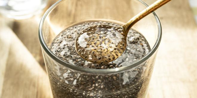 a glass of chia seeds in water, soaking into a gel that collects on a spoon