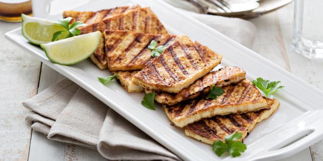 grilled tofu on a plate with limes and cilantro